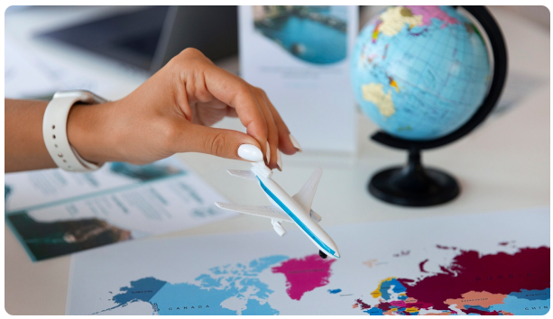 Hand placing a toy airplane on a world map beside a globe